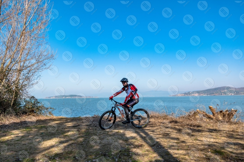 Trasimeno lake bike bicycle cyclist shore water sky clear sky panorama view landscape man San Feliciano Polvese Island  Trasimeno