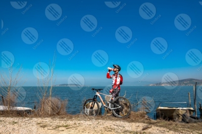 trasimeno Trasimeno Lake bike bicycle cyclist San Feliciano Polvese Island shore boats water sky clear sky panorama view landscape man