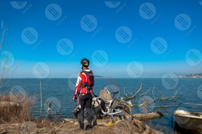 trasimeno Trasimeno Lake bike bicycle cyclist San Feliciano Polvese Island shore boats water sky clear sky panorama view landscape man