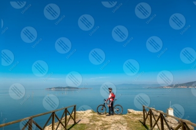 trasimeno Trasimeno Lake bike bicycle cyclist San Feliciano Polvese Island shore pathway water sky clear sky panorama view landscape man